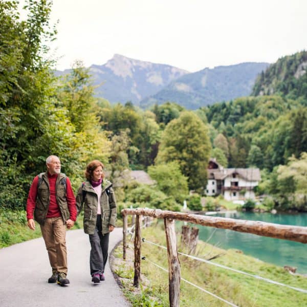 Retired couple happily walking on path near water in the mountains