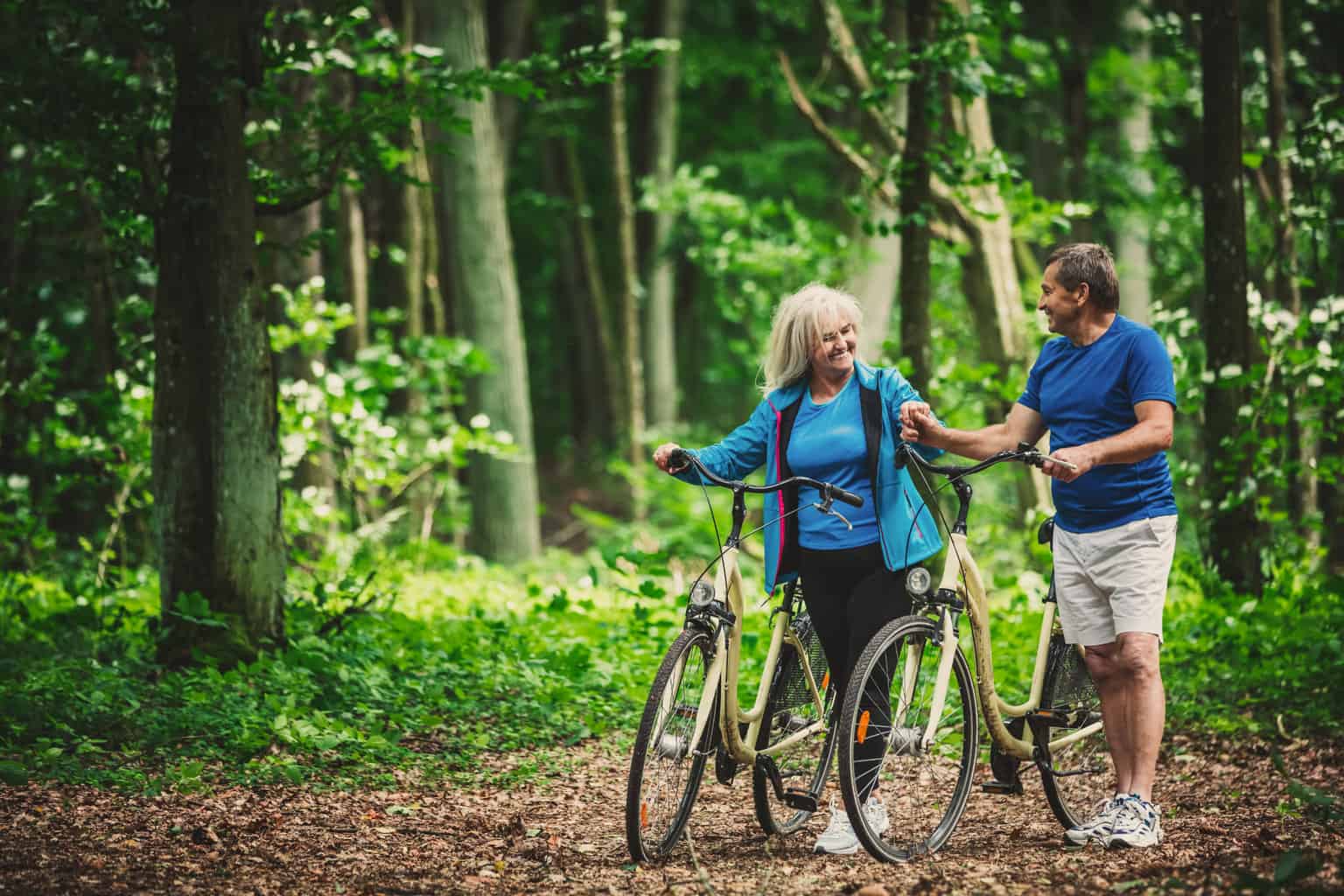 A retired couple riding bikes in the woods