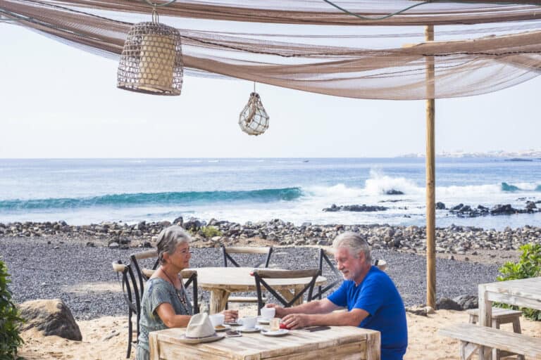 Retired couple enjoying a snack on the beach