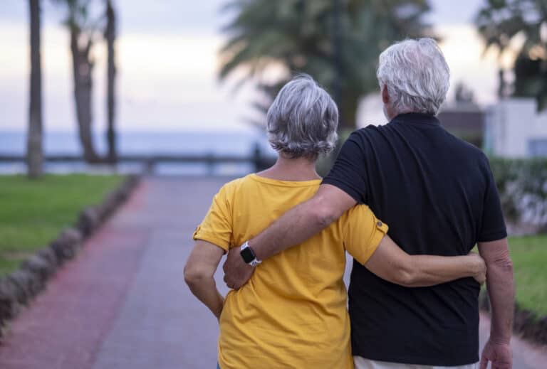 Retired couple walking down a path to the beach