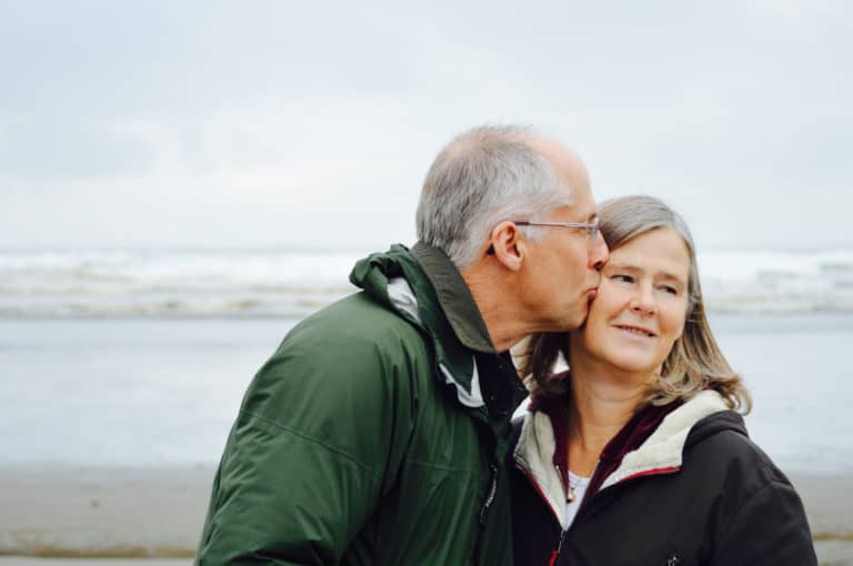 Husband kissing wife while on beach