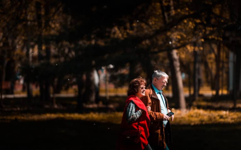 Retired couple walking through a park in the fall