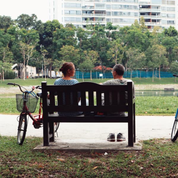 A couple sitting on a bench in a park in Singapore